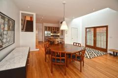 Opposite view. Open floor plan facing the front of the home. Stairway to second floor on left across from the kitchen. Doorway at the end of the hall leads to the garage, basement, and wine cellar. This space is finished with beautiful wood floor, recessed lighting, soaring ceilings, and lot of natural daylight.