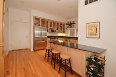 The kitchen was tastefully updated with black quartz counters, wood cabinets with glass fronts, stainless steel appliances, recessed lighting, and counter/bar seating.