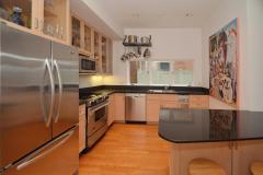 The kitchen was tastefully updated with black quartz counters, wood cabinets with glass fronts, stainless steel appliances, recessed lighting, and counter/bar seating.