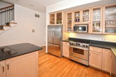 The kitchen was tastefully updated with black quartz counters, wood cabinets with glass fronts, stainless steel appliances, recessed lighting, and counter/bar seating.