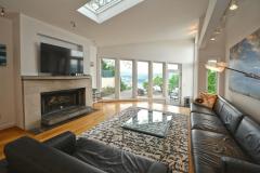 The living room has beautiful wood floors, lots of natural light from every angle, a wood burning fireplace, accent lighting, skylight, walk-out to the tiered deck, and dog/cat door for your furry friends.