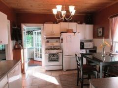 Kitchen boasts wood ceiling, tile floor, window, newer light fixture, white cabinets, newer countertop, and white appliances.