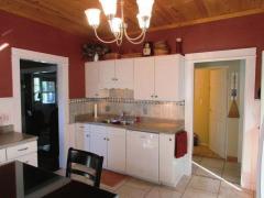 Charming kitchen boasts a wood ceiling, white cabinets with a beautiful neutral backsplash, and a tile floor.