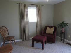 Alternate view of the room with the exterior door. Hardwood under carpet floor covering.