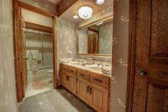 This bathroom has chandelier, double sinks, bath tub and shower.