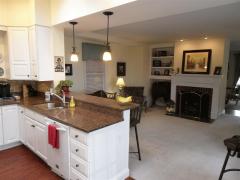 A view of the living room with kitchen and bar. Pendant lighting.