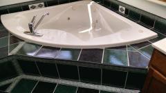 Corner raised whirlpool tub with ceramic tile.