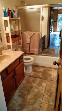 Main floor guest bath with ceramic tile flooring and tub/shower, marble sink, mirrored glass shower door.