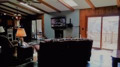 Two sets of wood sliders with views of woods and expansive restained deck that runs along back of home.
